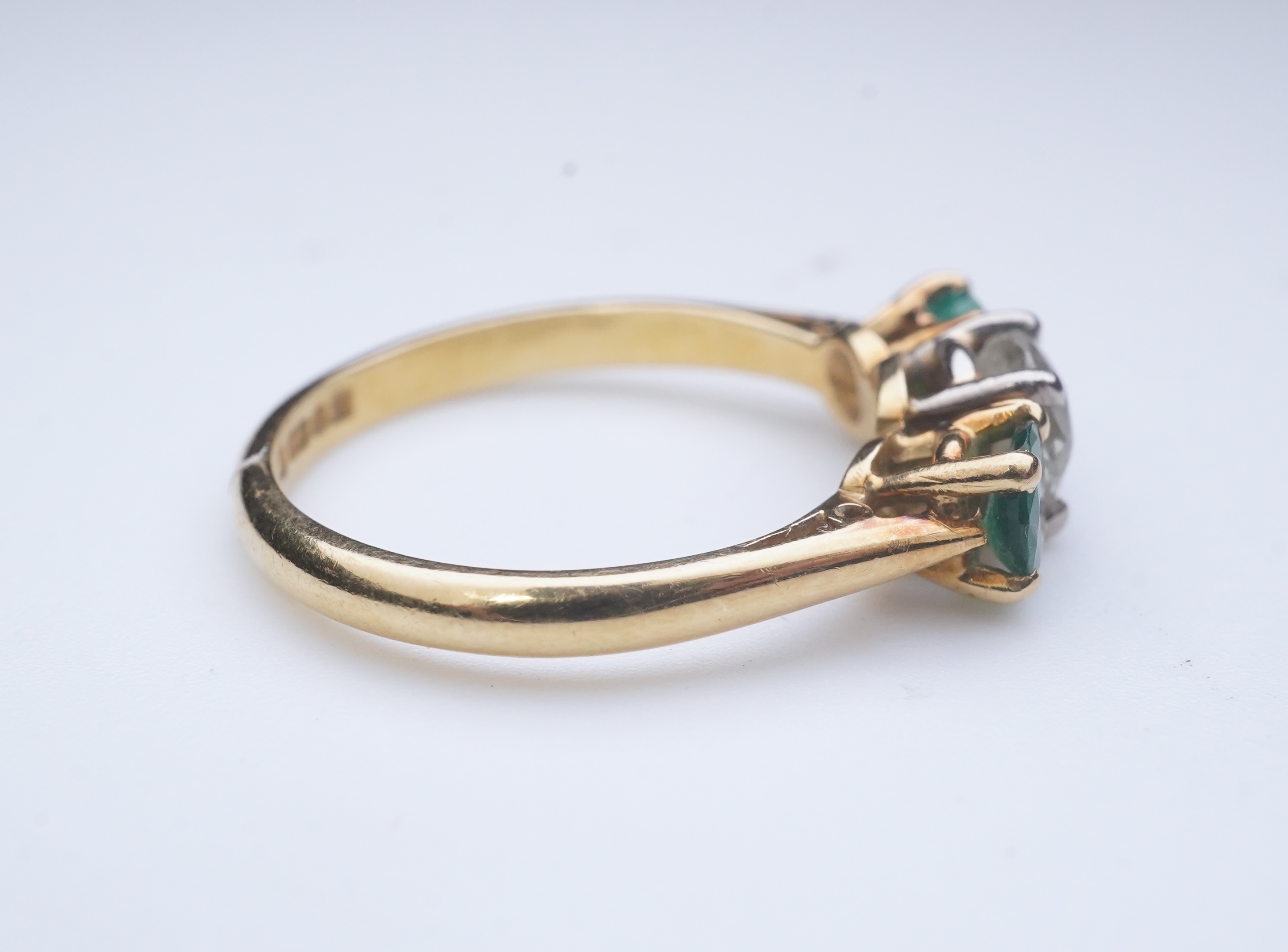 An emerald and diamond three-stone ring